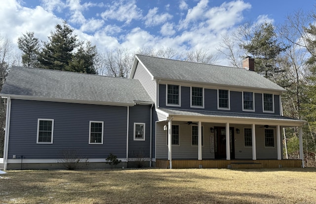 colonial house with covered porch, a front lawn, a chimney, and a ceiling fan