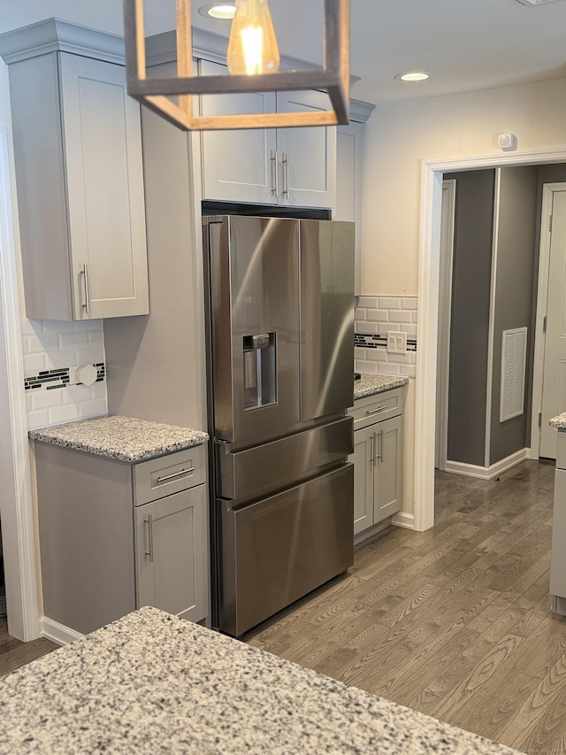 kitchen featuring visible vents, decorative backsplash, light wood-style flooring, and stainless steel fridge with ice dispenser