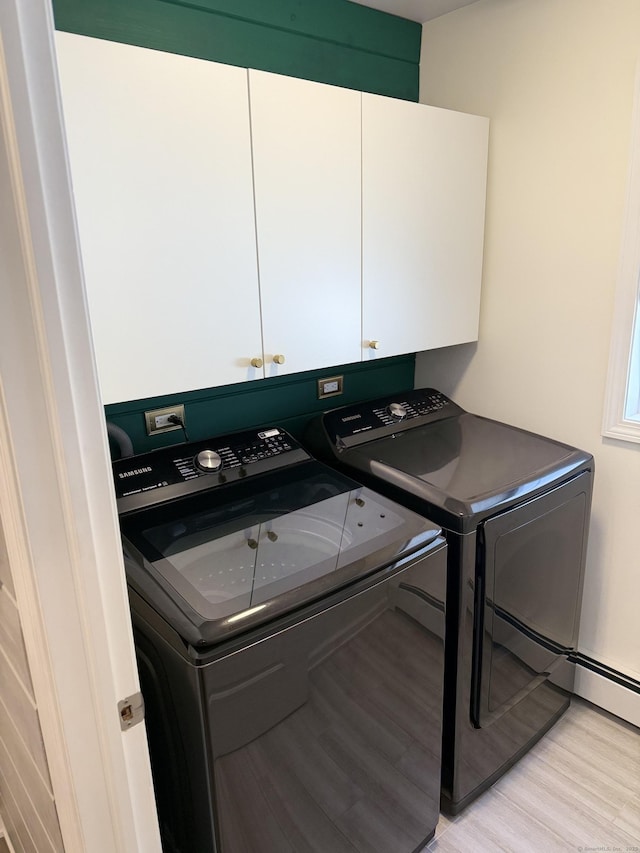 laundry area featuring cabinet space, light wood finished floors, and washer and clothes dryer