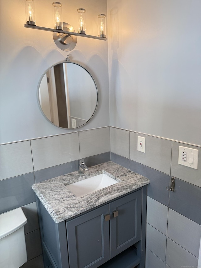 bathroom featuring vanity, tile walls, and toilet