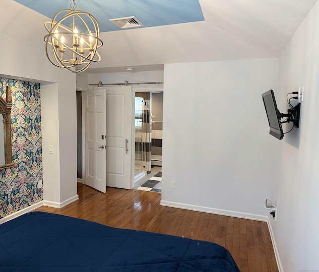 bedroom with a barn door, baseboards, visible vents, and hardwood / wood-style floors