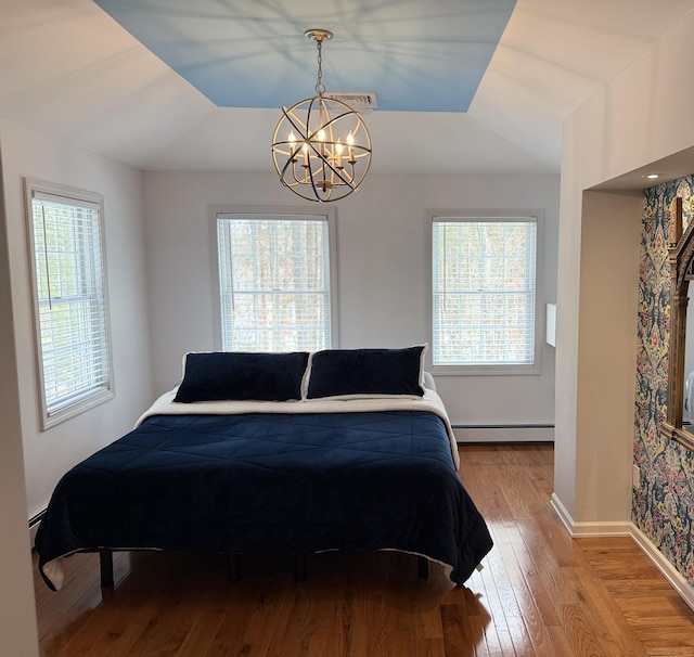 bedroom featuring visible vents, baseboards, a chandelier, hardwood / wood-style floors, and baseboard heating