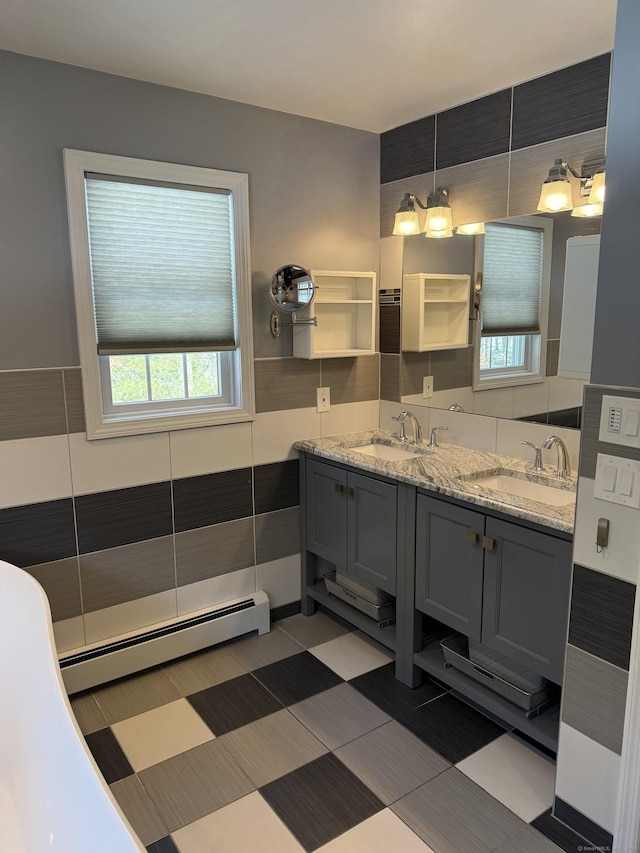 full bath featuring double vanity, baseboard heating, and a sink