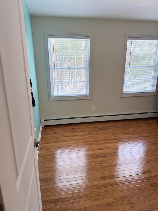 empty room featuring hardwood / wood-style floors and a baseboard radiator