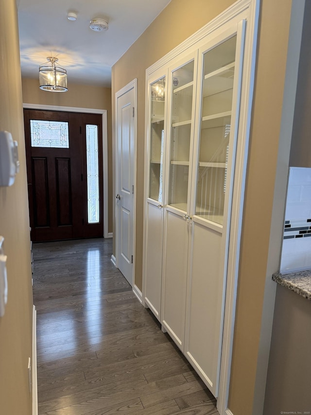 entrance foyer with an inviting chandelier and dark wood-style flooring