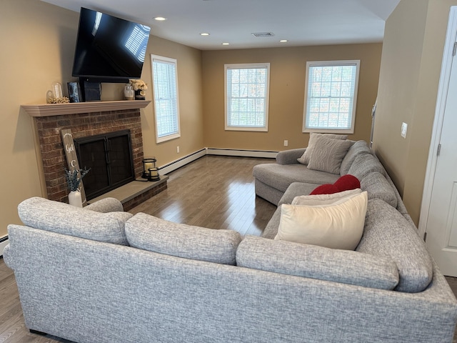 living room with a brick fireplace, recessed lighting, wood finished floors, and visible vents