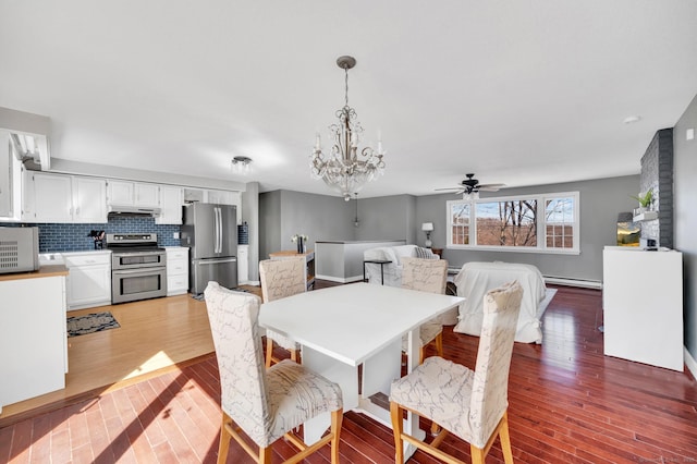 dining space with ceiling fan with notable chandelier, wood finished floors, and baseboard heating