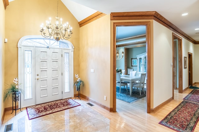 entryway featuring light wood finished floors, visible vents, baseboards, ornamental molding, and an inviting chandelier