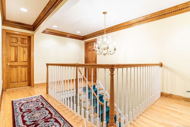 hallway with an upstairs landing, a notable chandelier, wood finished floors, crown molding, and baseboards