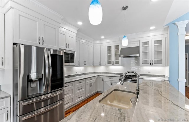 kitchen with a sink, white cabinetry, stainless steel appliances, wall chimney range hood, and glass insert cabinets