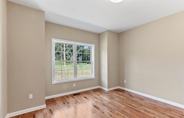 unfurnished room with visible vents, wood finished floors, and baseboards