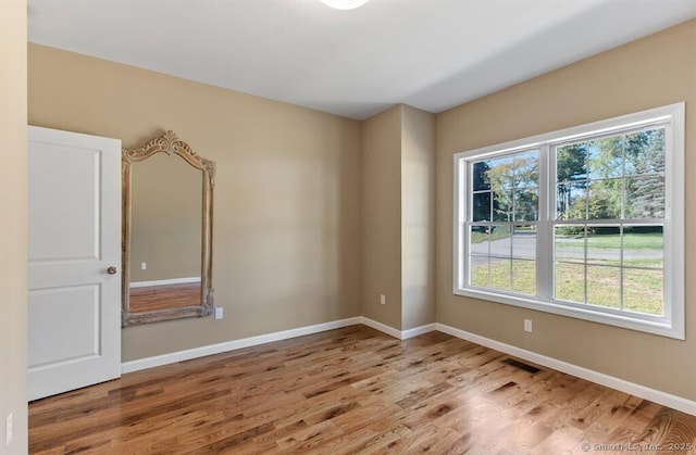 unfurnished room featuring wood finished floors, visible vents, and a wealth of natural light