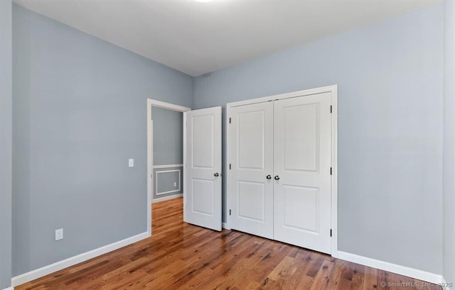 unfurnished bedroom with a closet, baseboards, and wood finished floors