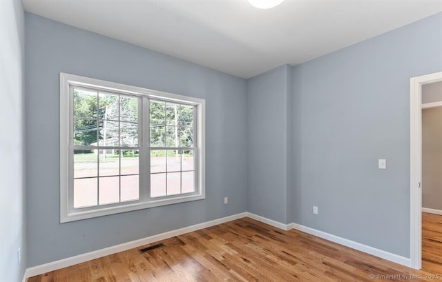 unfurnished room featuring visible vents, baseboards, and wood finished floors