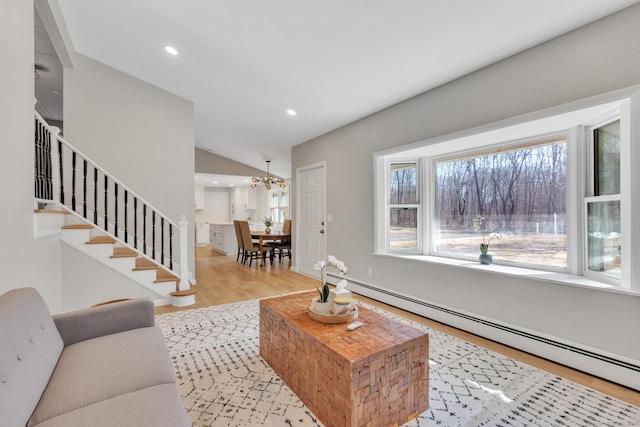 living room featuring stairway, light wood-type flooring, baseboard heating, recessed lighting, and a notable chandelier