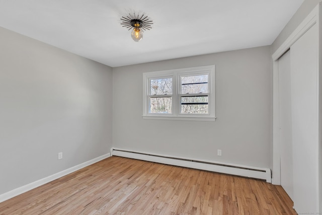 spare room featuring baseboard heating, light wood-type flooring, and baseboards