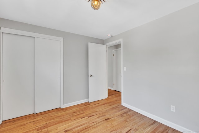 unfurnished bedroom featuring a closet, baseboards, and wood finished floors