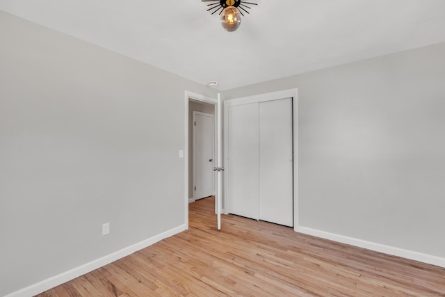 unfurnished bedroom with a closet, baseboards, and light wood-style floors