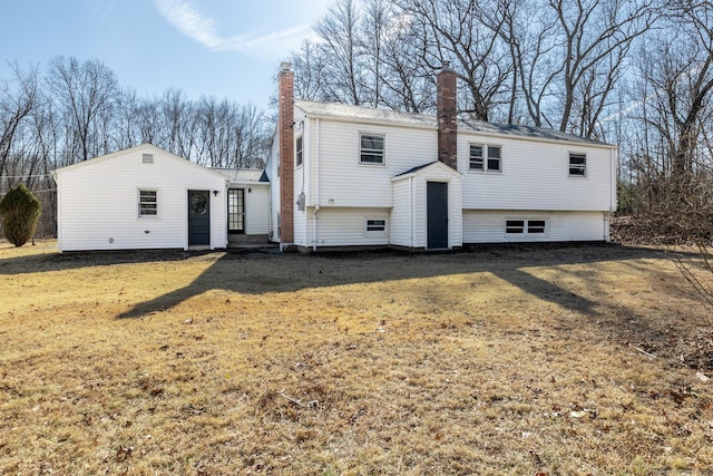 back of house with a lawn and a chimney