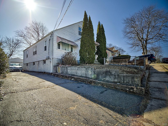 view of side of property with aphalt driveway and fence