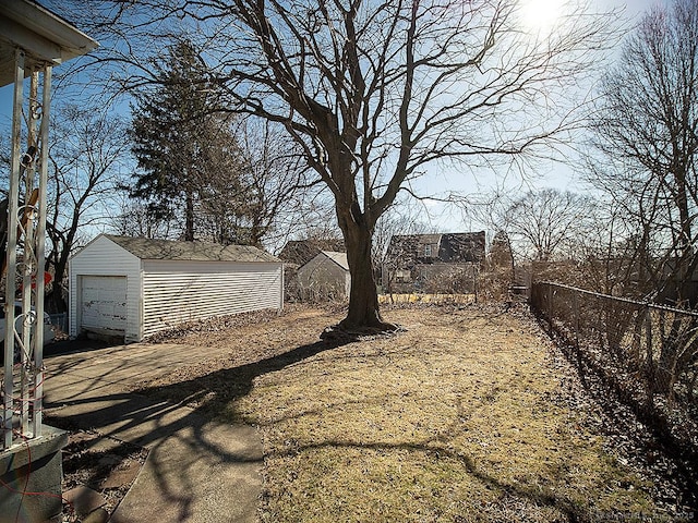 view of yard with a detached garage, an outdoor structure, and fence