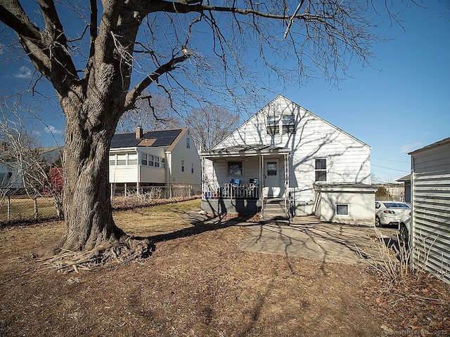 back of house featuring a porch and fence