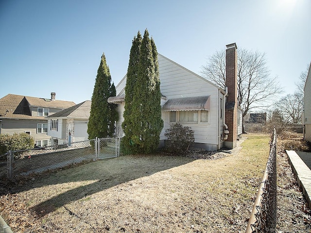 exterior space with a chimney, fence, and a gate