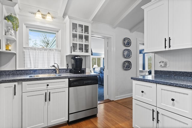 kitchen with beam ceiling, a sink, stainless steel dishwasher, wood finished floors, and white cabinets