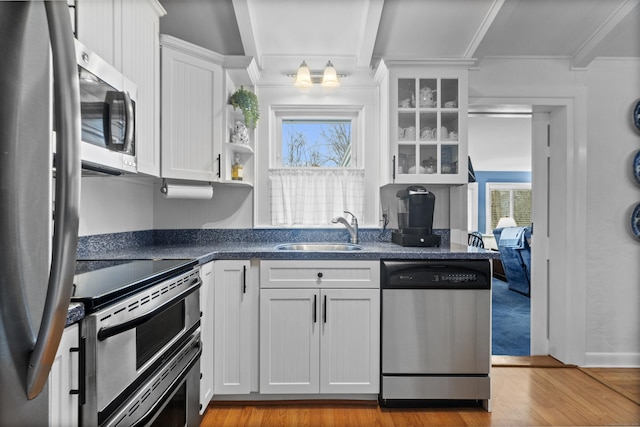 kitchen featuring dark countertops, white cabinets, appliances with stainless steel finishes, and a sink