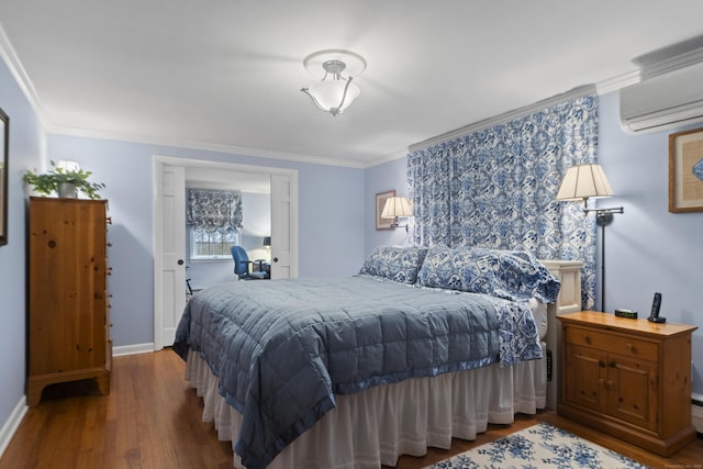 bedroom featuring an AC wall unit, wood finished floors, crown molding, and baseboards