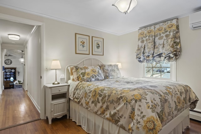 bedroom featuring crown molding, baseboards, wood-type flooring, and a wall mounted AC