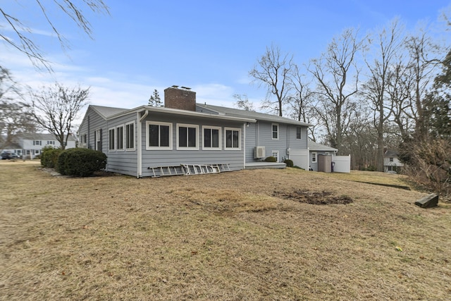 rear view of house featuring a lawn and a chimney