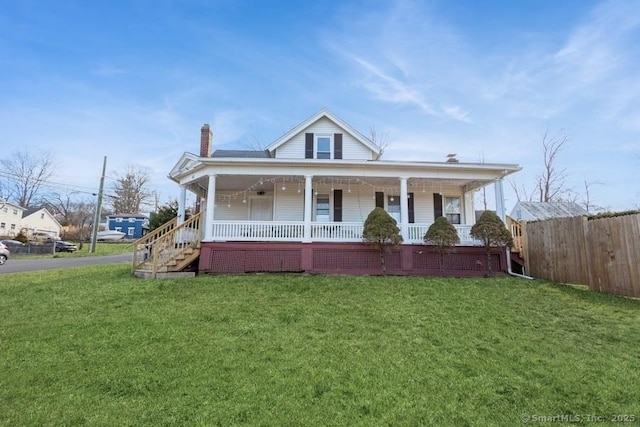 farmhouse inspired home featuring covered porch, a chimney, a front lawn, and fence