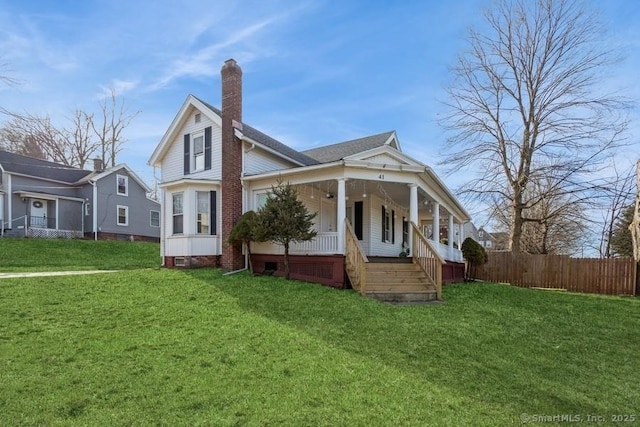 back of property featuring fence, covered porch, a chimney, crawl space, and a lawn