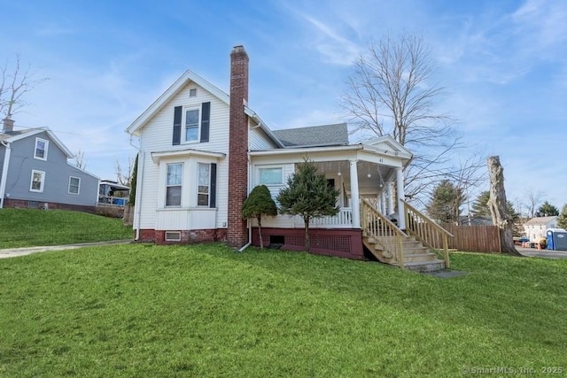 rear view of house featuring a lawn, a porch, fence, roof with shingles, and a chimney