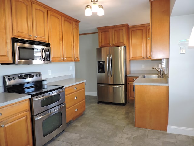 kitchen with light countertops, baseboards, appliances with stainless steel finishes, and a sink