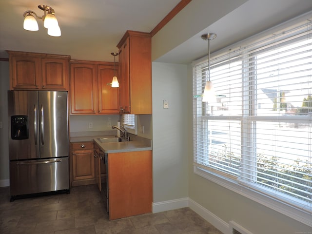 kitchen with light countertops, black dishwasher, brown cabinetry, stainless steel fridge, and a sink