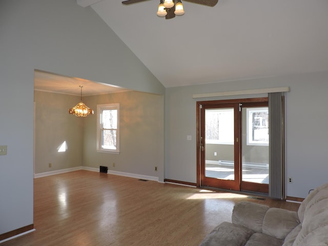 unfurnished living room with wood finished floors, visible vents, baseboards, high vaulted ceiling, and ceiling fan with notable chandelier