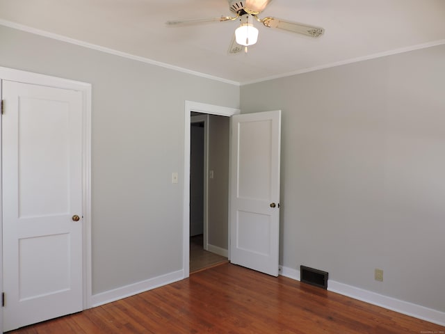 spare room featuring visible vents, ornamental molding, baseboards, and wood finished floors