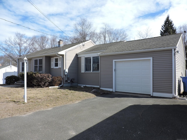 single story home featuring aphalt driveway, an attached garage, roof with shingles, and a chimney