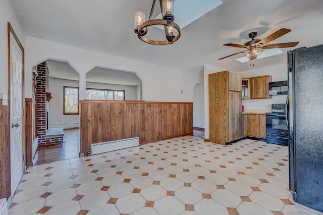 kitchen featuring brown cabinetry, arched walkways, black appliances, and a baseboard heating unit