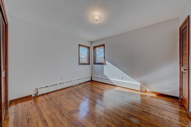 empty room with baseboard heating and wood finished floors