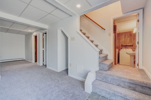 stairway featuring a baseboard radiator, a paneled ceiling, and washer / dryer