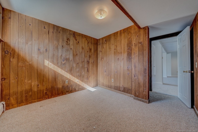 carpeted empty room with baseboard heating and wood walls