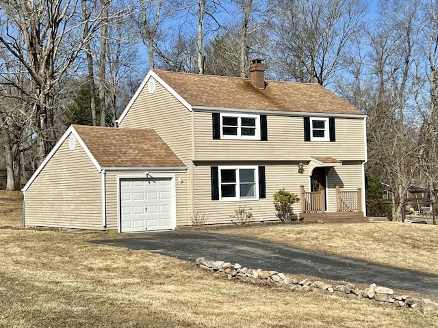 colonial inspired home featuring a front yard, an attached garage, driveway, and a chimney