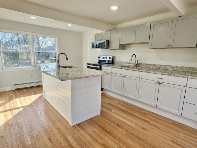 kitchen featuring stainless steel appliances, a baseboard heating unit, light wood-style floors, and a sink