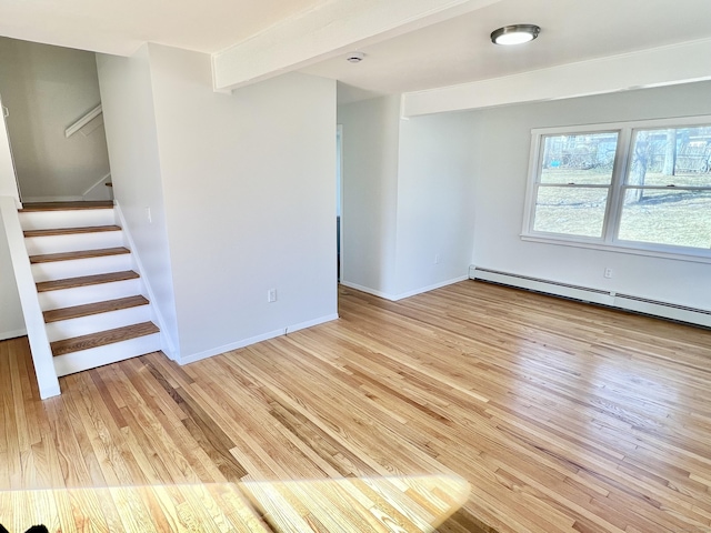 empty room with beam ceiling, light wood-style floors, baseboards, baseboard heating, and stairs