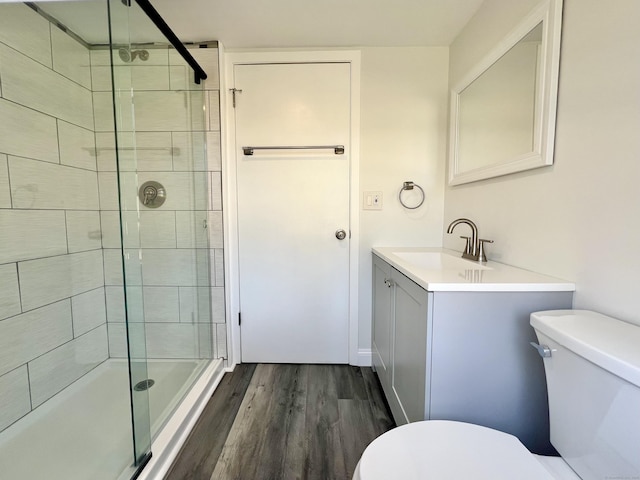 bathroom featuring vanity, a shower stall, toilet, and wood finished floors