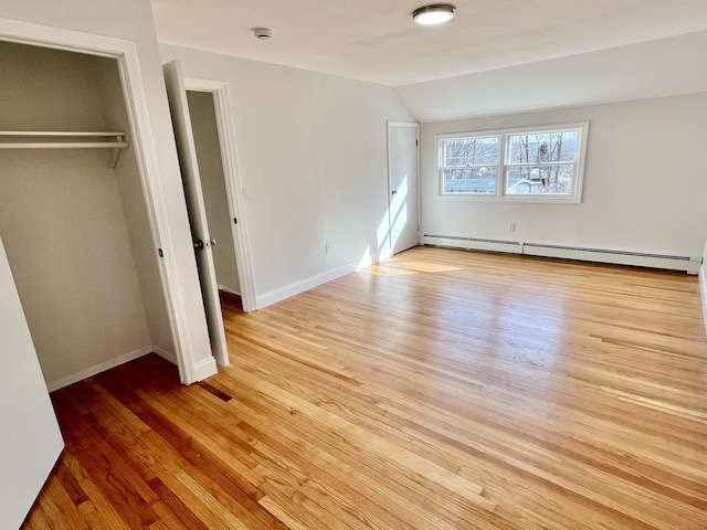 unfurnished bedroom featuring baseboards, a closet, light wood-style floors, a baseboard radiator, and lofted ceiling