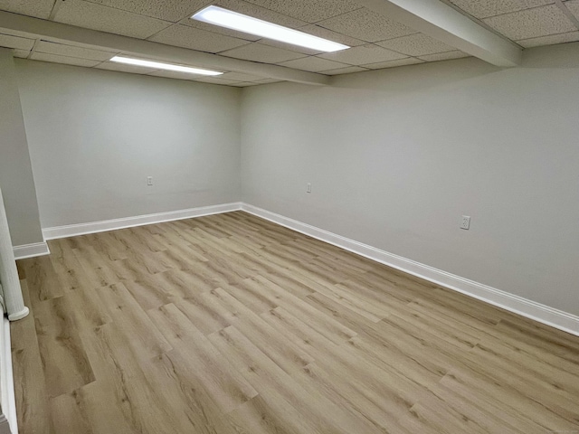 spare room featuring wood finished floors, baseboards, and a drop ceiling